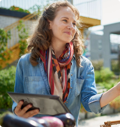 Woman holding a tablet outdoors, smiling